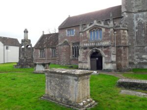 alt="tombstone, preaching cross & front door of church"
