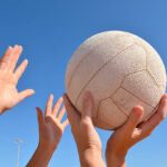alt="hands reaching for a netball"