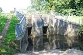 alt="two square openings under a bridge with a fence"